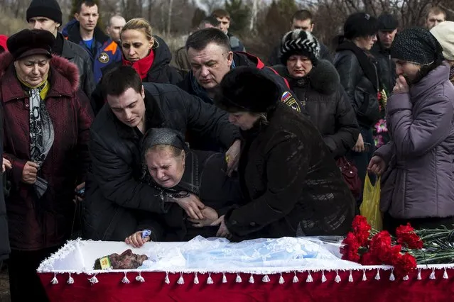 Relatives of a worker Dmitri Aleksandrov, killed by a blast at the Zasyadko coal mine, mourn next to his coffin during a funeral ceremony in Donetsk, Ukraine March 6, 2015. (Photo by Marko Djurica/Reuters)