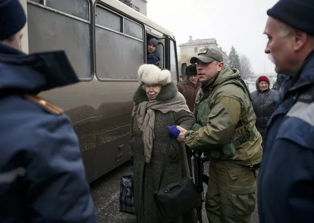 A member of the Ukrainian armed forces assists local residents onto a bus to flee the military conflict, in Debaltseve, eastern Ukraine, February 6, 2015. (Photo by Gleb Garanich/Reuters)