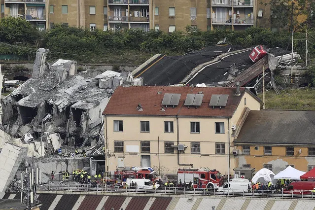 Rescuers work among the rubble of the collapsed Morandi highway bridge in Genoa, northern Italy, Tuesday, August 14, 2018. A large section of the bridge collapsed over an industrial area in the Italian city of Genova during a sudden and violent storm, leaving vehicles crushed in rubble below. (Photo by Flavio Lo Scalzo/ANSA via AP)