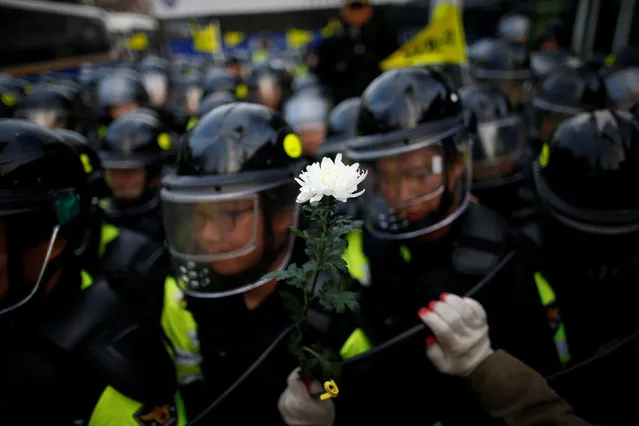 A man holding a flower leans on a shield of a riot policeman as they march toward the Presidential Blue House during a protest calling for South Korean President Park Geun-hye to step down in central Seoul, South Korea, December 3, 2016. (Photo by Kim Hong-Ji/Reuters)