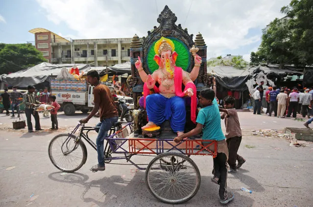 Devotees transport an idol of the Hindu god Ganesh, the deity of prosperity, in a rickshaw to a place of worship on the first day of the ten-day-long Ganesh Chaturthi festival, in Ahmedabad, India, September 13, 2018. (Photo by Amit Dave/Reuters)