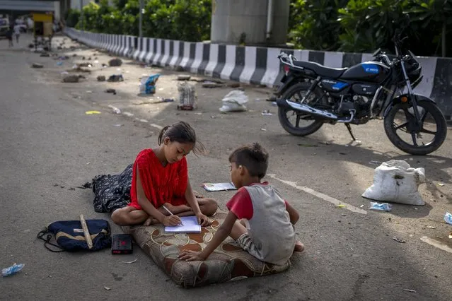 Children of migrant farm workers study on a mattress on an overpass after they evacuated their homes on the flooded banks of the Yamuna River more than month ago, in New Delhi, India, Wednesday, August 9, 2023. At the leader’s summit in September G-20 countries will get one final chance to send a strong message of climate action. (Photo by Altaf Qadri/AP Photo)
