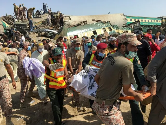 Paramilitary soldiers and rescue workers move a body of a man from the site following a collision between two trains in Ghotki, Pakistan on June 7, 2021. (Photo by Reuters/Stringer)