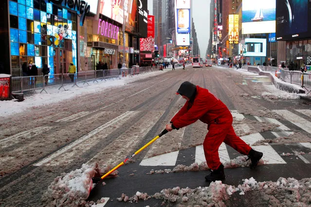 A worker clears the snow from the crosswalk in Times Square, Manhattan, New York City, U.S. December 17, 2016. (Photo by Andrew Kelly/Reuters)