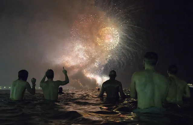People watch the fireworks exploding over Copacabana beach during the New Year's Eve celebrations in Rio de Janeiro, Brazil, Sunday, January 1, 2017. (Photo by Leo Correa/AP Photo)