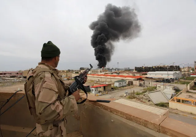 A member from the Iraqi security forces looks at smoke rising in Tikrit April 1, 2015. (Photo by Alaa Al-Marjani/Reuters)