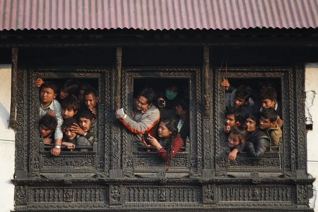 Nepalese people watch from the window of a Hindu temple the cremation of Nepalese prime minister Sushil Koirala, on the banks of the Bagmati River in Kathmandu, Nepal, Wednesday, February 10, 2016. Koirala, who was a key figure in the drafting and adoption of the country's new constitution in 2015, died Tuesday at the age of 78. (Photo by Niranjan Shrestha/AP Photo)