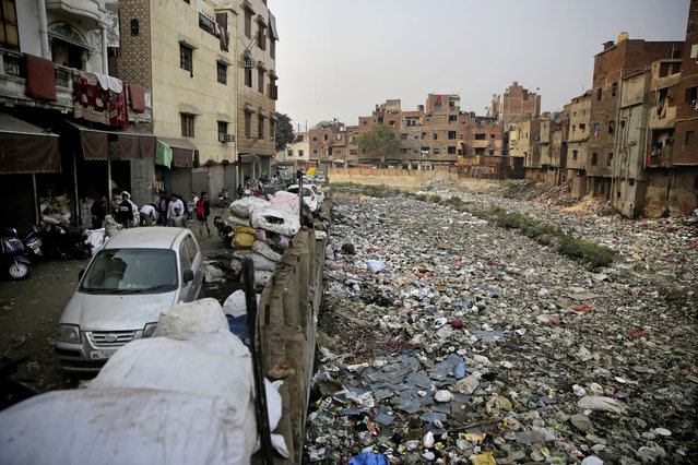 In this Saturday, December 8, 2018 photo piles of electronic waste is placed next to a drain chocked with plastic and garbage in New Delhi, India. (Photo by Altaf Qadri/AP Photo)