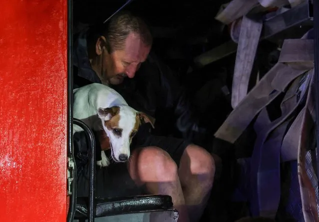 A man and a dog are seen inside a truck during emergency evacuation from a flooded street carried out by rescuers due to a storm warning in Yevpatoriya, Crimea on November 26, 2023. (Photo by Alexey Pavlishak/Reuters)