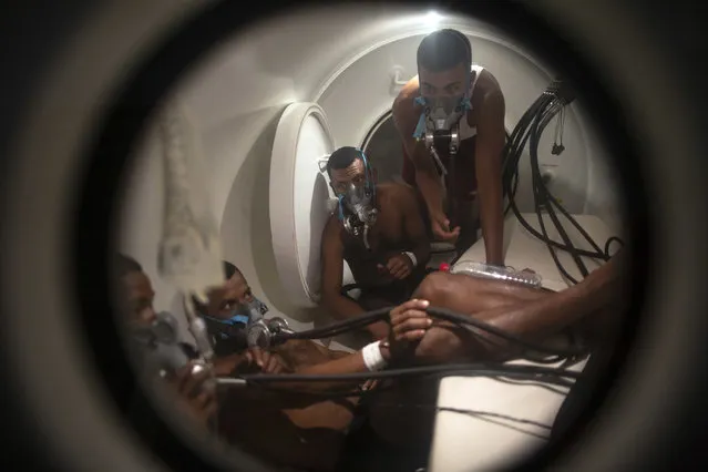 In this February 7, 2018 photo, Miskito divers stricken with decompression sickness climb into a hyperbaric chamber at the hospital in Puerto Lempira, Honduras. Standard diving techniques call for a gradual ascent to the surface to eliminate the nitrogen that the body's tissues absorb during a dive. But many of the divers of Mosquitia dive deeply, surface quickly and then go back for more, racing to collect as much lobster as possible. (Photo by Rodrigo Abd/AP Photo)