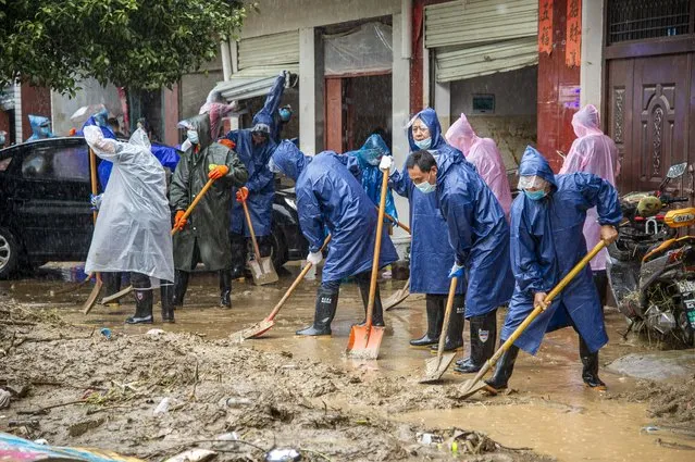 In this photo released by China's Xinhua News Agency, people shovel debris and mud from a road in Liulin Township of Suixian County in central China's Hubei Province, Friday, August 13, 2021. Flooding in central China continued to cause havoc in both cities and rural areas, with authorities saying Friday that more than 20 people had been killed and another several were missing. (Photo by Wu Zhizun/Xinhua via AP Photo)