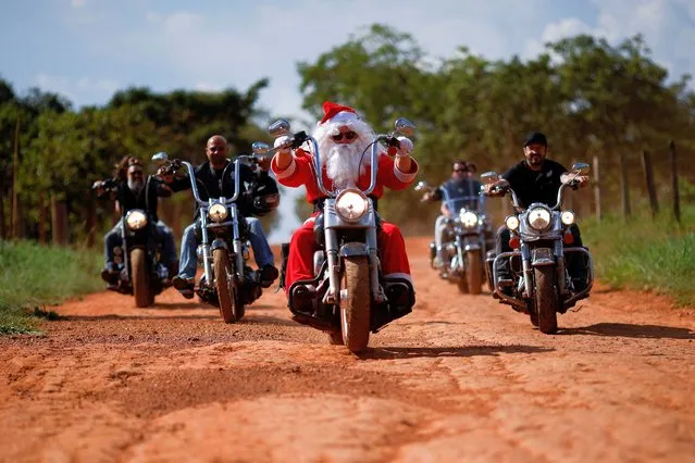 A motorcyclist, Helton Garcia dressed as Santa Claus, rides his motorcycle before handing out gifts to children in a rural school in Santo Antonio do Descoberto, state of Goias, Brazil on December 10, 2023. (Photo by Adriano Machado/Reuters)