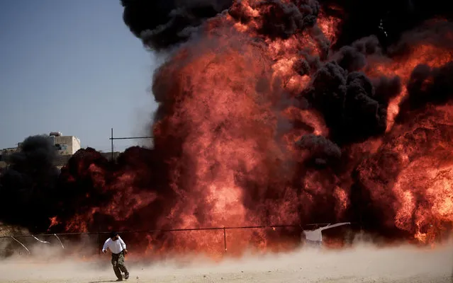 An Iranian man who was fixing explosives wires run away after setting ablaze 50 tons of drugs seized in recent months in eastern Tehran on June 26, 2013 to mark the International Day Against Drug Abuse and Illicit Trafficking. (Photo by Behrouz Mehri/AFP Photo)