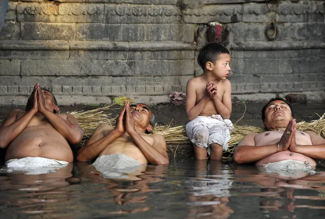 Nepalese Hindu devotees take part in a bathing ritual on the last day of the month-long Swasthani Festival in the Hanumante River at Bhaktapur on the outskirts of Kathmandu on February 22, 2016. Devotees mark the Swasthani Festival with fasting, and with women in particular undertaking rituals in the hope of a prosperous life for her family and conjugal happiness. (Photo by Prakash Mathema/AFP Photo)