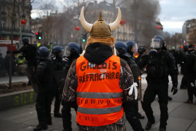 A demonstrator wearing a replica of a Gallic helmet with a vest reading “refractory Gallic” takes part to a yellow vest protest Saturday, February 2, 2019 in Paris. France's yellow vest protesters are taking to the streets to keep pressure on French President Emmanuel Macron's government, for the 12th straight weekend of demonstrations. This week, demonstrators in the French capital are planning to pay tribute to the yellow vests injured during clashes with police. (Photo by Francois Mori/AP Photo)