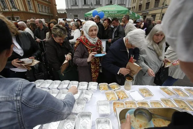 Bosnian people gather to taste chicken stew after cooks and volunteers prepared the stew in Sarajevo, on Friday April 17, 2015. (Photo by Amel Emric/AP Photo)