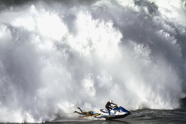 A jet ski pilot and a wakeboarder outrun a gigantic wave that crashes around them in Nazar, Portugal. (Photo by Andre Botelho/Caters News Agency)