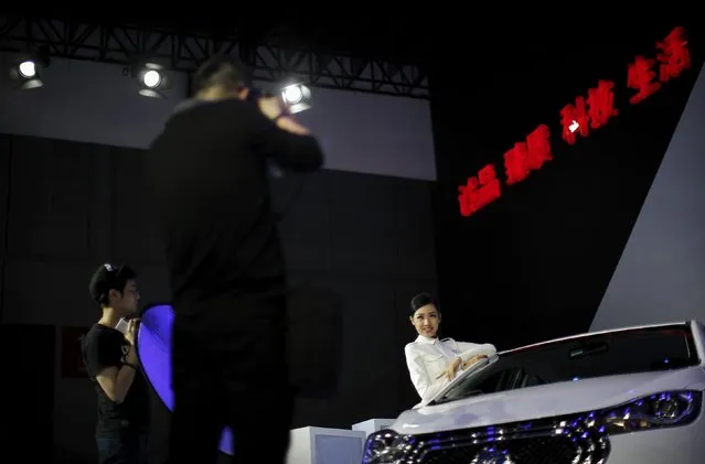 A model poses for pictures next to a JAC car during the 16th Shanghai International Automobile Industry Exhibition in Shanghai, April 20, 2015. (Photo by Carlos Barria/Reuters)