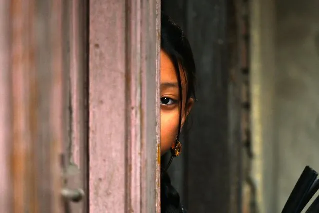 A girl watches the members of Nepali ethnic Newar community participating in “Jyapu Day” celebrations that marks the end of the harvest season, in Kathmandu on December 26, 2023. (Photo by Prakash Mathema/AFP Photo)