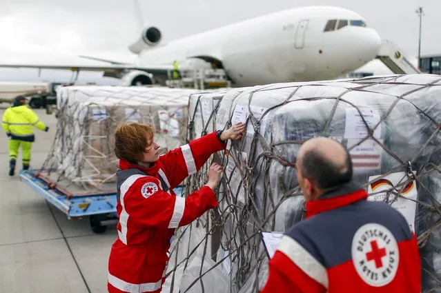Workers of the German Red Cross (DRK) prepare a load of humanitarian aid for victims of the earthquake in Nepal, in front of an aircraft at Schoenefeld airport outside Berlin April 27, 2015. The flight will carry around 60 tonnes of supplies for the victims. (Photo by Hannibal Hanschke/Reuters)