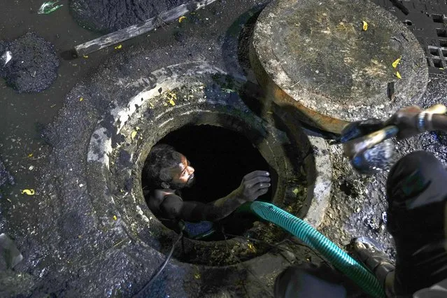 A worker cleans a manhole on a street in Hyderabad, India, Sunday, January 21, 2024. (Photo by Mahesh Kumar A./AP Photo)