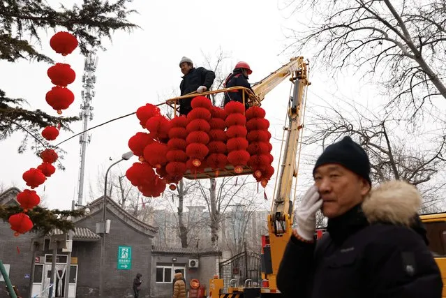 Workers hang lantern decorations on a tree ahead of Lunar New Year at a park in Beijing, China, on January 30, 2024. (Photo by Tingshu Wang/Reuters)
