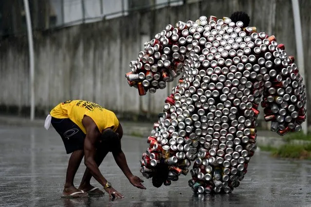 A local helps a reveler with his costume made from beer and soda cans during the “Bloco da Latinha” street party Carnival parade in Madre de Deus, Brazil, Sunday, February 11, 2024. (Photo by Eraldo Peres/AP Photo)
