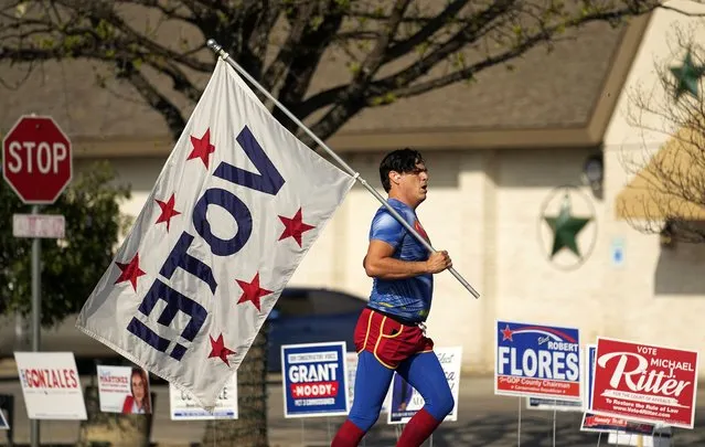 Dressed as Superman and holding a “Vote!” flag, Artist David Alcantar jogs past a polling site, Tuesday, March 5, 2024, in San Antonio. The flag and costume are part of an art project to encourage voting. (Photo by Eric Gay/AP Photo)