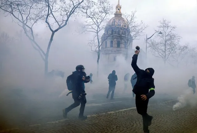 A protester throws a projectile amid tear gas during clashes near the Invalides during a demonstration against French government's pension reform plan in Paris as part of a national strike and protests in France on January 31, 2023. (Photo by Gonzalo Fuentes/Reuters)