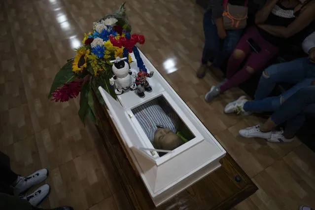 Toys adorn the coffin of 4-year-old Joshue Acevedo the day after he died during his wake in Caracas, Venezuela, Wednesday, October 27, 2021. (Photo by Ariana Cubillos/AP Photo)
