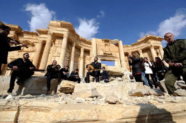 A Russian soldier stands near Syrian musicians as they play their instruments while resting on damage in the amphitheater of the historic city of Palmyra, Syria March 4, 2017. (Photo by Omar Sanadiki/Reuters)