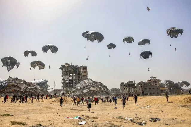 People rush to landing humanitarian aid packages dropped over the northern Gaza Strip on April 23, 2024 amid the ongoing conflict in the Palestinian territory between Israel and the militant group Hamas. (Photo by AFP Photo/Stringer)