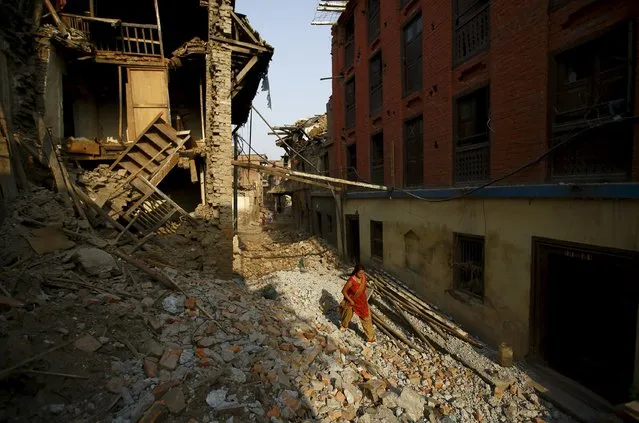 A woman walks along a street near collapsed houses, a month after the April 25 earthquake in Kathmandu, Nepal May 25, 2015. (Photo by Navesh Chitrakar/Reuters)