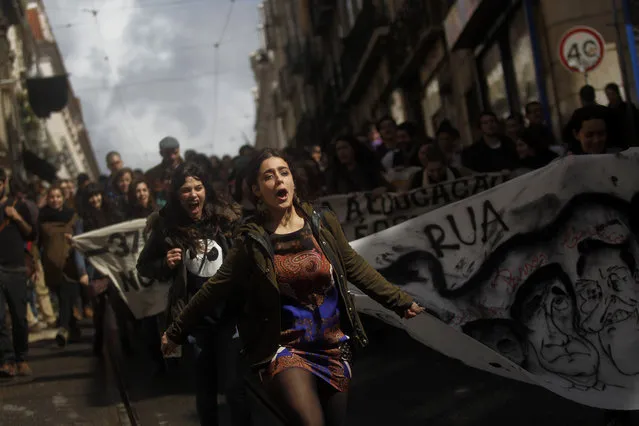 People run and shout slogans as they march towards the Portuguese parliament during a protest by Portuguese university students in Lisbon, Wednesday, April 2, 2014. The protest was against cuts in the public education system. The white banner on the right with the faces of the Portuguese Prime Minister Pedro Passos Coelho and the Portuguese President Anibal Cavaco Silva reads in Portuguese: “Out”. (Photo by Francisco Seco/AP Photo)