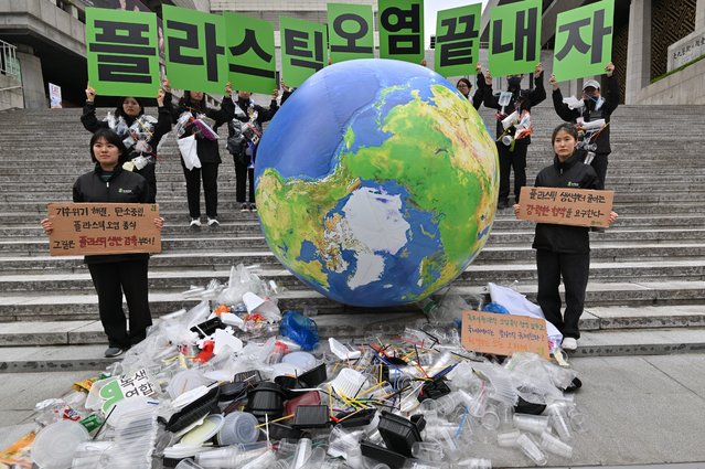 Environmental activists hold up placards reading “Let's end plastic pollution!” as they display plastic waste with an earth balloon during a campaign event to mark the international Earth Day in Seoul on April 22, 2024. (Photo by Jung Yeon-je/AFP Photo)