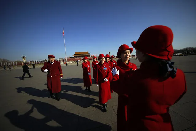 In this Sunday, March 5, 2017 photo, a hospitality staffer poses her colleagues for photographs on Tiananmen Square during the National People's Congress held at the Great Hall of the People in Beijing. Dressed in vermillion coats, colorful scarves and high-heeled boots, the well-coiffed young women accompany delegates to China's rubberstamp legislature to the Great Hall of the People then hold signs up to guide them back to their buses. In between, the women move on to the equally important tasks of taking selfies and posing for painstakingly composed group photos. (Photo by Andy Wong/AP Photo)