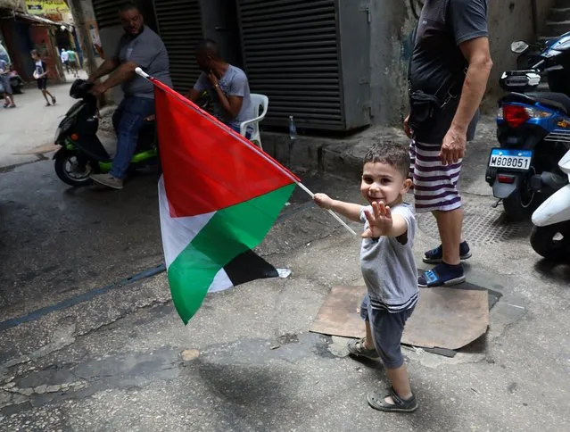 A boy carries a flag of Palestine in an alley of the Palestinian refugee camp of Shatila in Lebanon's capital Beirut, on May 21, 2021. From marching in rallies to posting live updates on social media, Palestinian refugee Mira Krayem has barely slept since conflict gripped her ancestral homeland earlier this month. But the 24-year-old university student, who lives in Lebanon, said she felt solidarity messages for the Palestinian cause from across the world have made her and fellow activists feel reenergized after years of crushing defeat. (Photo by Anwar Amro/AFP Photo)