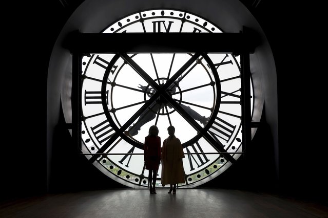 China's President Xi Jinping's wife Peng Liyuan, right, and French President Emmanuel Macron's wife Brigitte Macron pose in front of the clock as they visit the Orsay Museum, Monday, May 6, 2024 in Paris. (Photo by Aurelien Morissard/AP Photo)