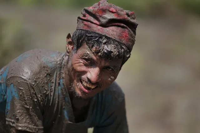 A Nepalese farmer reacts to the camera as they play with sludge while planting paddy saplings in a field on the outskirts of Kathmandu, Nepal, Tuesday, June 30, 2015. (Photo by Niranjan Shrestha/AP Photo)