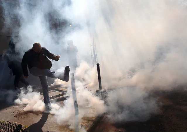 A masked protestor kicks a tear gas canister during clashes with riot police as part of the traditional May Day march in Paris, France, Sunday, May 1, 2016. The traditional May Day rallies are taking on greater weight this year in France as Parliament is debating a bill that would allow longer working hours and let companies lay workers off more easily. (Photo by Michel Spingler/AP Photo)