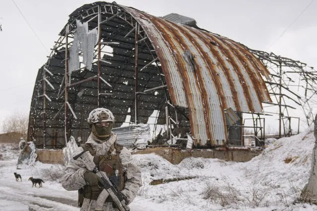 A Ukrainian serviceman provides area security during a visit by Gen. Oleksandr Pavliuk, commander of the Joint Forces Operation, to frontline positions in a former industrial area, outside Avdiivka, Donetsk region, eastern Ukraine, Wednesday, February 9, 2022. (Photo by Vadim Ghirda/AP Photo)