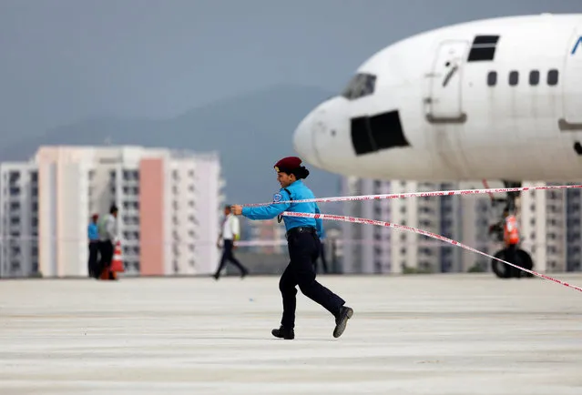 A police personnel runs holding a police line tape to secure an area near the plane during an emergency drill simulating a bomb attack at the Tribhuvan International Airport in Kathmandu, Nepal on June 28, 2019. (Photo by Navesh Chitrakar/Reuters)