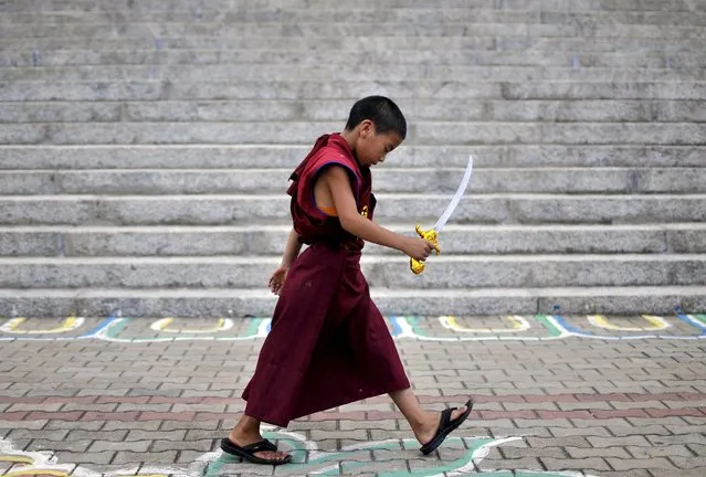 A novice Tibetan monk walks while holding a toy sword as he attends celebrations marking the 80th birthday of the Tibetan spiritual leader, the Dalai Lama, at the Sera Jey Monastery in Bylakuppe in the southern state of Karnataka, India, July 6, 2015. (Photo by Abhishek N. Chinnappa/Reuters)