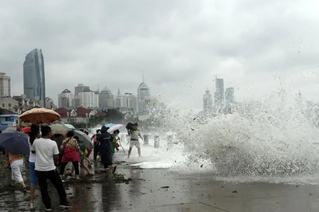 People run away from massive waves hit the seacoast of Qingdao in east China's Shandong province Sunday, July 12, 2015. (Photo by Chinatopix via AP Photo)