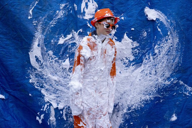 An orange-clad boy waits for people to pay to throw pies during King's Day celebrations in Amsterdam, Netherlands, Thursday, April 27, 2023. The Netherlands celebrated the 56th birthday of King Willem-Alexander of the House of Orange on Thursday with street markets, parties and pastries, even as polls showed the monarch's popularity declining. (Photo by Peter Dejong/AP Photo)