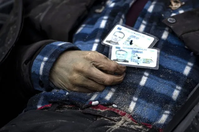 Identification cards rest on a man as policemen work to identify people following the killing of civilians in Bucha, before sending the bodies to the morgue, on the outskirts of Kyiv, Ukraine, Wednesday, April 6, 2022. (Photo by Rodrigo Abd/AP Photo)