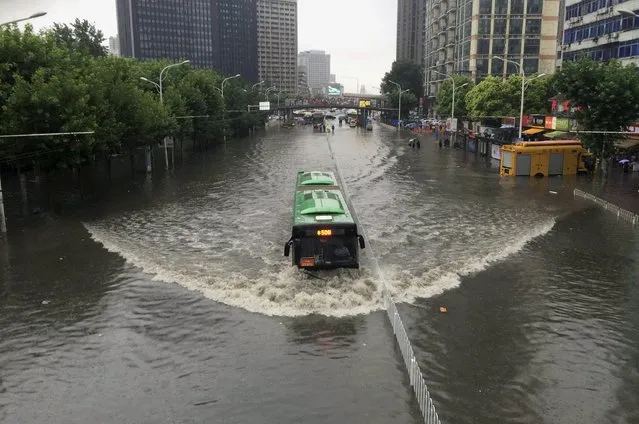 A bus travels along a flooded street as heavy rainfall hit Wuhan, Hubei province, China, July 23, 2015. (Photo by Reuters/Stringer)