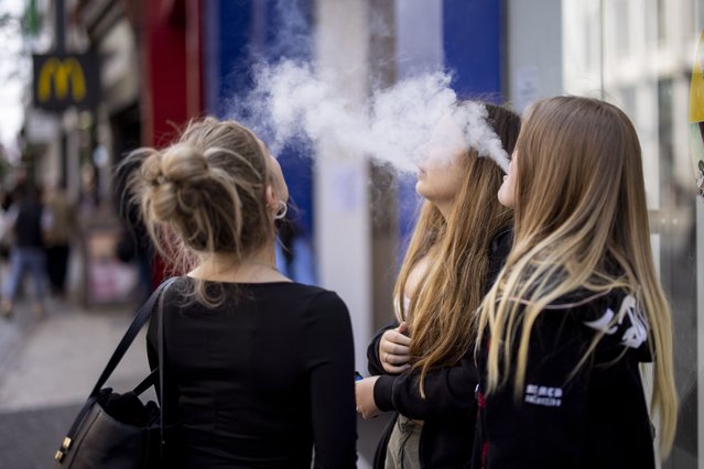 Young people use single-use vaping products in London, Britain, 30 May 2023. The UK government has announced it is cracking down on retailers providing free vape samples to children. The government's new proposals include rules on fines for shops selling illicit vapes to children under 18-years-old. (Photo by Tolga Akmen/EPA)