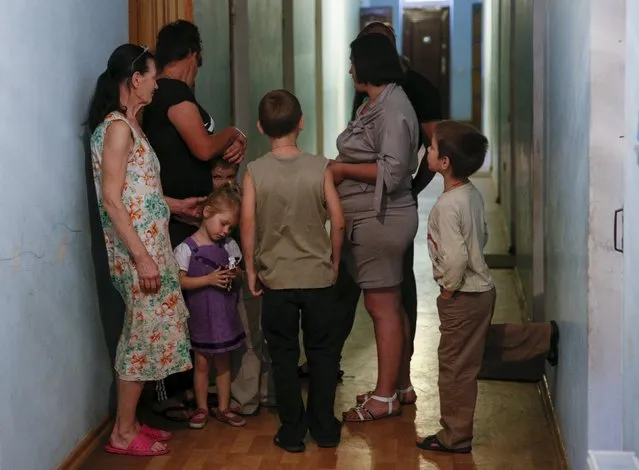 People gather in a corridor inside a building on the compound of a health and rest centre temporarily serving as accommodation for refugees from the eastern regions of the country in the town of Korostyshiv, Zhytomyr region, Ukraine, July 30, 2015. More than 400 people who left eastern Ukraine due to a military conflict have arrived at the sanatorium in Korostyshiv since the summer of 2014, according to representatives. (Photo by Valentyn Ogirenko/Reuters)
