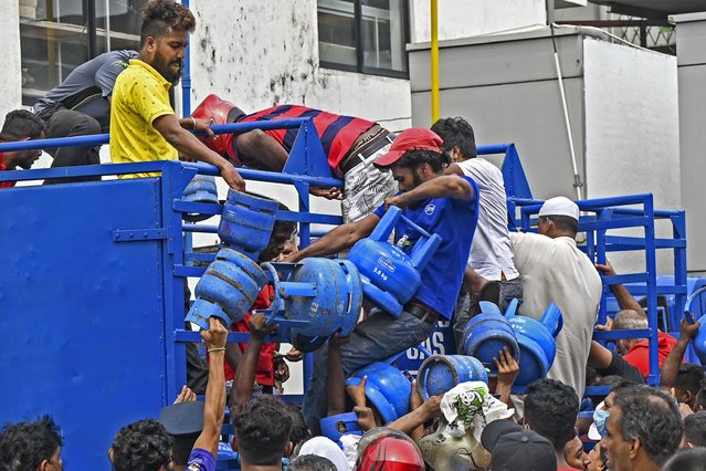 Enraged crowd loot a truck transporting cooking gas cylinders in Colombo on May 8, 2022, who had been waiting in line overnight for supplies. Outnumbered police watched helplessly as men climbed onto the truck and got away with 84 cylinders of gas, officials said. (Photo by Ishara S. Kodikara/AFP Photo)